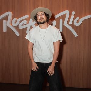 Zeeba investe em um visual casual chic com influências do estilo boho urbano. O cantor combina uma camiseta branca básica de modelagem solta com calça oversized de lavagem escura e pernas amplas, finalizando a produção com chapéu de aba larga em tom neutro, óculos de armação fina e colar delicado