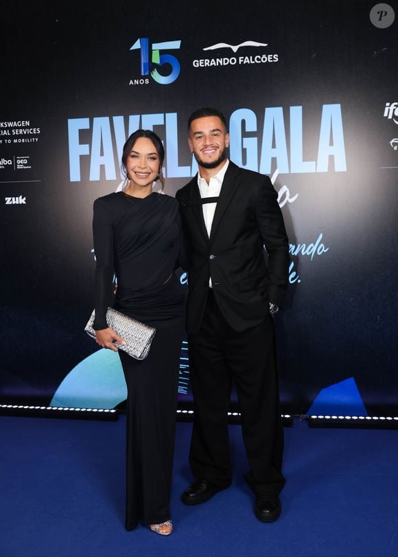 Philippe Coutinho e esposa Ainê Coutinho: ela vestiu um vestido preto longo de mangas compridas, com decote canoa e detalhes drapeados na cintura e finalizou o look com uma clutch prateada texturizada e sandálias pretas de salto alto. Ele usava um terno preto clássico, camisa branca de botões e sapatos sociais pretos
