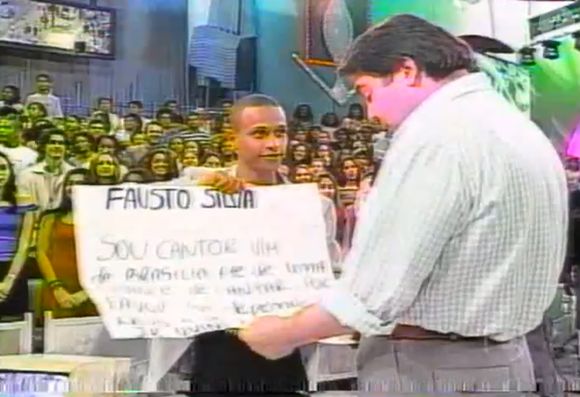 Faustão teve a atenção chamada por Mano Junior, cantor que levou um cartaz para a plateia do 'Domingão' em julho de 1999
