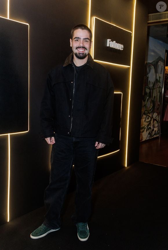 Filho de Faustão, João Guilherme Silva aposta em uma estética urbana e minimalista com uma proposta inteiramente voltada para tons escuros. Ele veste uma jaqueta de sarja preta estruturada, de modelagem ampla estilo oversized, caracterizada por lapelas proeminentes e fechamento em zíper frontal. Por baixo, complementa com uma camiseta básica preta de gola careca. A parte inferior é composta por uma calça jeans preta de corte reto e lavagem discreta