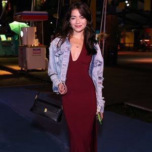Anna Rita Cerqueira escolheu um vestido longo na cor vinho com um decote profundo em V e fenda lateral discreta. Contrastando com o tom sofisticado da peça, ela usou uma jaqueta jeans clara de modelagem oversized com detalhes bem destroyed nos braços, completando com bolsa de ombro preta estruturada e botas escuras de bico quadrado