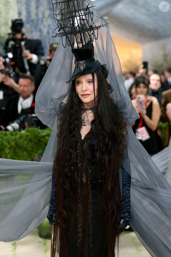 Ícone absoluto! Madonna transformou o Met Gala 2026 em palco para arte viva, surgindo com uma instalação impactante: um barco como adorno de cabeça e tecidos fluidos que evocavam o mar. Em preto total, a rainha do pop entregou drama, conceito e presença