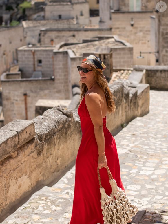 Paolla Oliveira usou vestido vermelho longo, com caimento leve. A bolsa boho de macramê e o lenço estampado na cabeça deram um toque artesanal à produção
