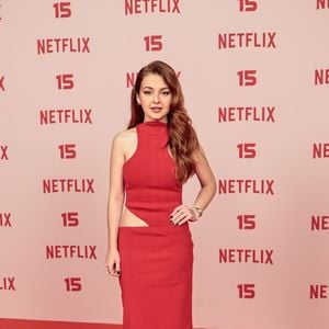 Klara Castanho: usa um vestido longo vermelho em tom fechado com gola alta e sem mangas, apresentando um recorte discreto estilo cut-out na lateral da cintura, combinado com sandálias claras de tiras finas