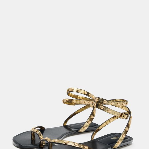 Toque orgânico em evidência! A sandália rasteira da Zara de R$ 279 chega com acabamento laminado e tiras delicadas com tachas metálicas em formato de conchas, unindo sofisticação e estética natural no mesmo design