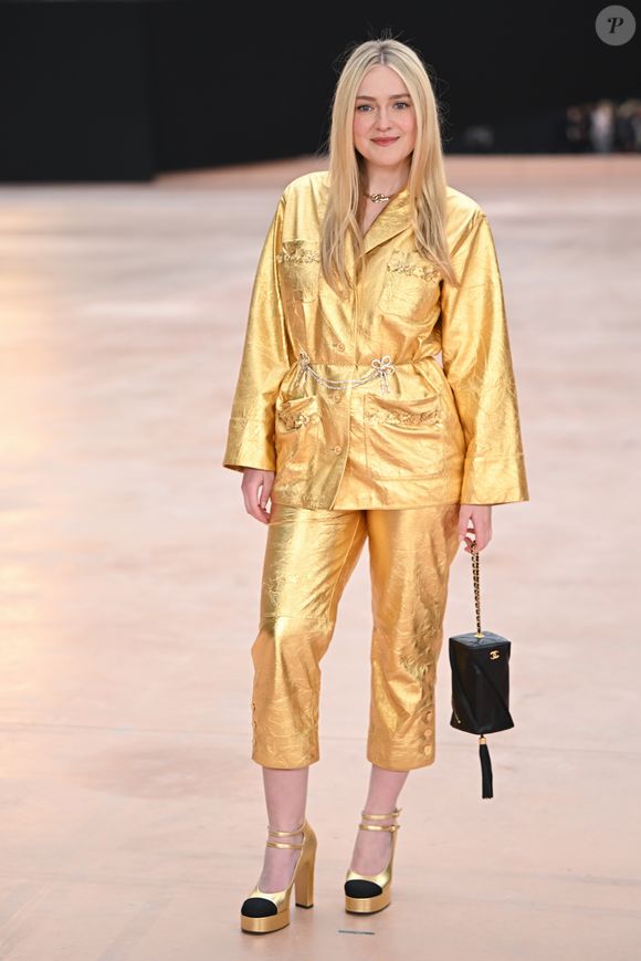 Dakota Fanning usa terninho metálico combinando com calça e sandália de salto dourados na Semana de Moda de Paris 2025.