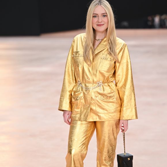 Dakota Fanning usa terninho metálico combinando com calça e sandália de salto dourados na Semana de Moda de Paris 2025.