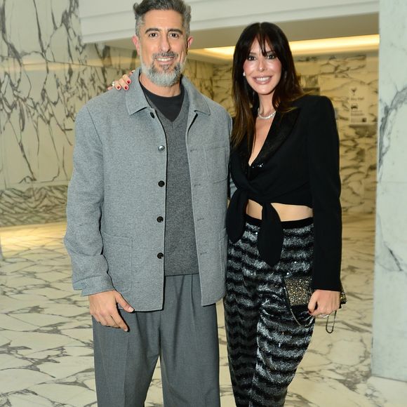 Suzana Gullo apostou na tendência glow com uma calça de alfaiataria em listras horizontais brilhantes texturizadas, combinada a um top cropped preto transpassado com amarração frontal e blazer clássico estruturado. O visual clean de Marcos Mion contrastou com a produção da esposa, trazendo um conjunto monocromático cinza composto por calça oversized, suéter de gola V e jaqueta de botões, arrematado por tênis casuais estampados