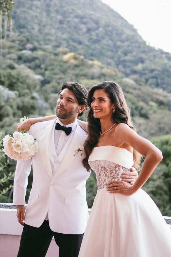 O modelo traz a sofisticação de uma noiva que transita entre universos. Na cerimônia, Yasmin apareceu com uma silhueta de princesa contemporânea: saia ampla em alfaiataria minimalista que equilibra a delicadeza do corpete estruturado em renda bordada.