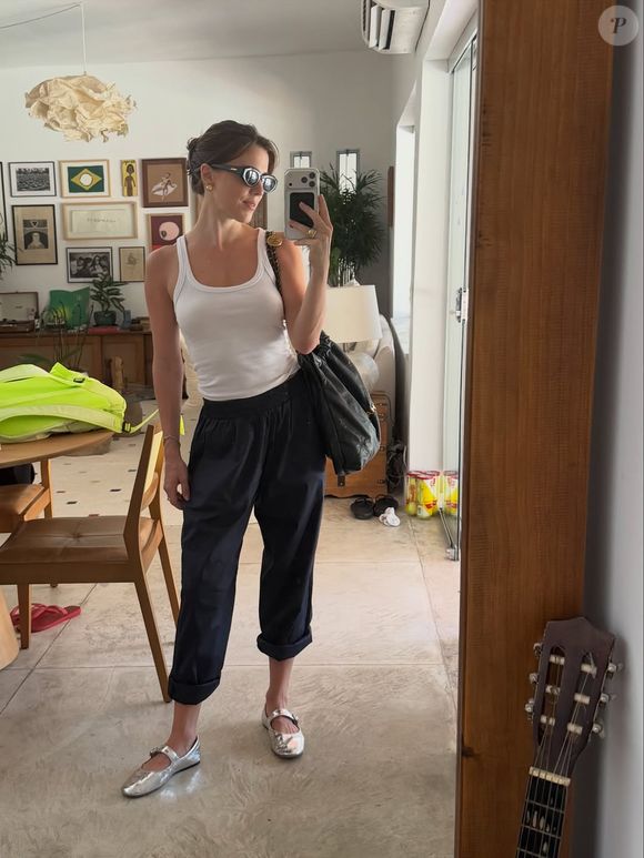 A atriz surge com regata branca ajustada, peça curinga que valoriza a silhueta sem esforço, combinada à calça preta de modelagem ampla, com barra dobrada, trazendo um ar relaxado e atual. É aquele visual que é  “despretensiosamente elegante”, como define o próprio street style contemporâneo