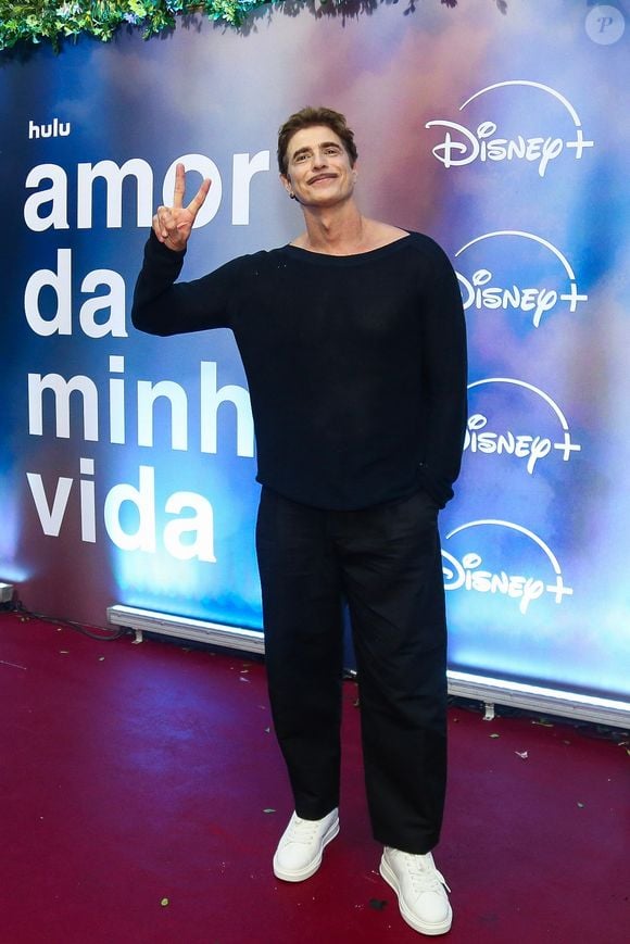 Reynaldo Gianecchini: apresenta uma proposta minimalista e descontraída em um conjunto de blusa preta de manga longa com gola canoa e calça de alfaiataria reta preta, completando o look com tênis brancos