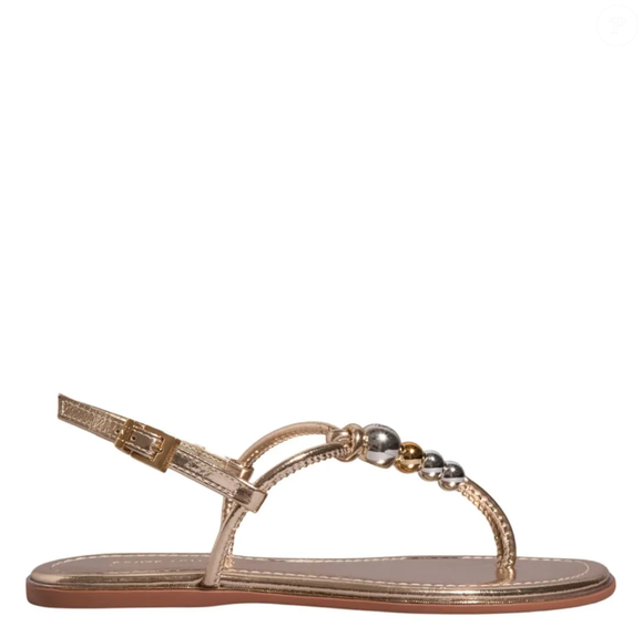 A Rasteira Metalizada Dourada da Santa Lolla apresenta bico redondo, com fechamento em fivela e pedrinhas decorativas, trazendo visual descontraído.