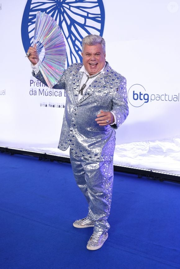 Milton Cunha: Visual maximalista e festivo composto por um terno inteiramente coberto de paetês brilhantes em tom azul-escuro metalizado com lapelas clássicas pretas. A peça foi combinada com uma camisa preta por baixo e um broche de pedrarias prateadas na lapela