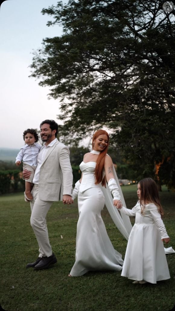 O vestido de noiva usado por Viih Tube no casamento civil tem acabamento em cetim, decote tomara que caia e uma modelagem ajustada ao corpo. As luvas completaram a produção