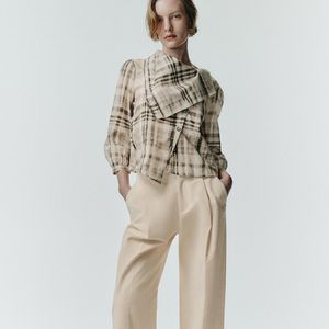 Entre os destaques da coleção da Zara está a Camisa Xadrez Lenço, uma peça cinza com gola tipo lenço, mangas abaixo do cotovelo e fechamento frontal cruzado com botões