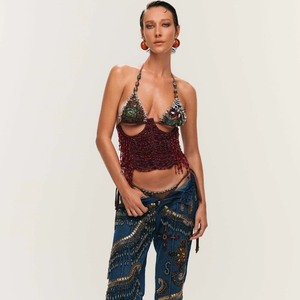 A produção aposta em calça jeans de lavagem escura, de modelagem reta, com bordados ondulares em tons de dourado, vermelho e cobre, que acrescentam personalidade e sofisticação ao visual.