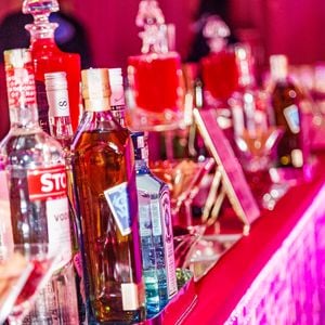 O bar da festa de 5 anos da WePink ganha iluminação rosa, painéis brilhantes e uma estante com perfumes da marca