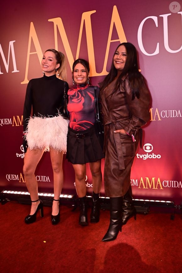 Samira, Gabi e Chayane, do 'BBB 26': o trio exibiu versatilidade com Samira em seu look de plumas, Gabi em um top estampado com padronagem de rosa e saia plissada, e Chayane em um elegante sobretudo de couro marrom de corte clássico