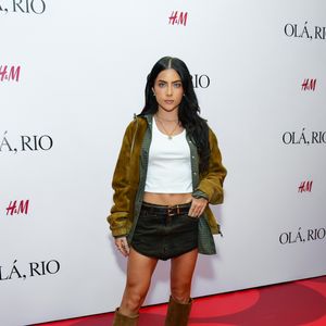 Jade trouxe uma proposta western core urbana, composta por uma minissaia jeans de lavagem escura e um top branco básico estilo cropped. A sobreposição contou com uma camisa xadrez em tons de verde sob uma jaqueta de camurça mostarda com fechamento em zíper