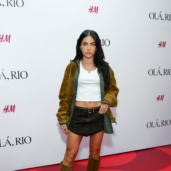 Jade trouxe uma proposta western core urbana, composta por uma minissaia jeans de lavagem escura e um top branco básico estilo cropped. A sobreposição contou com uma camisa xadrez em tons de verde sob uma jaqueta de camurça mostarda com fechamento em zíper