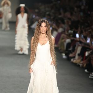 A atriz elevou a produção com uma sobreposição de colares dourados de diferentes comprimentos e medalhões, além de brincos de argola minimalistas. O destaque final ficou para a beleza natural, com os cabelos longos e ondulados em cascata, harmonizando perfeitamente com a proposta orgânica e fluida do visual