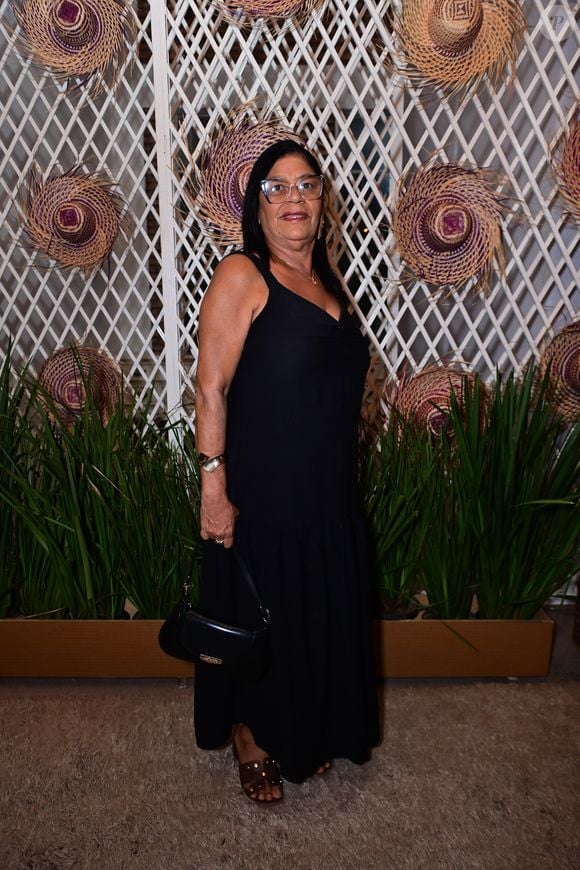 Dona Delma: exibiu elegância clássica em um vestido longo preto de alças grossas e decote em V, caracterizado por um leve babado na barra texturizada. A produção foi complementada por uma bolsa de ombro de couro preta estruturada, óculos de grau com armação transparente e sandálias abertas escuras