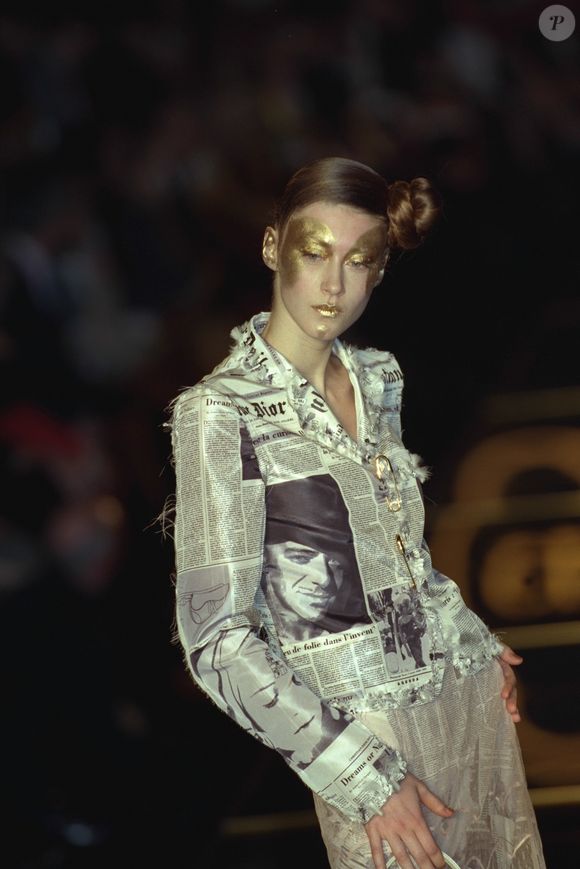 O rosto estampado no 'jornal' que aparece em peças como esse blazer é do próprio John Galliano, uma referência direta ao designer homenageado pelo Met Gala 2027