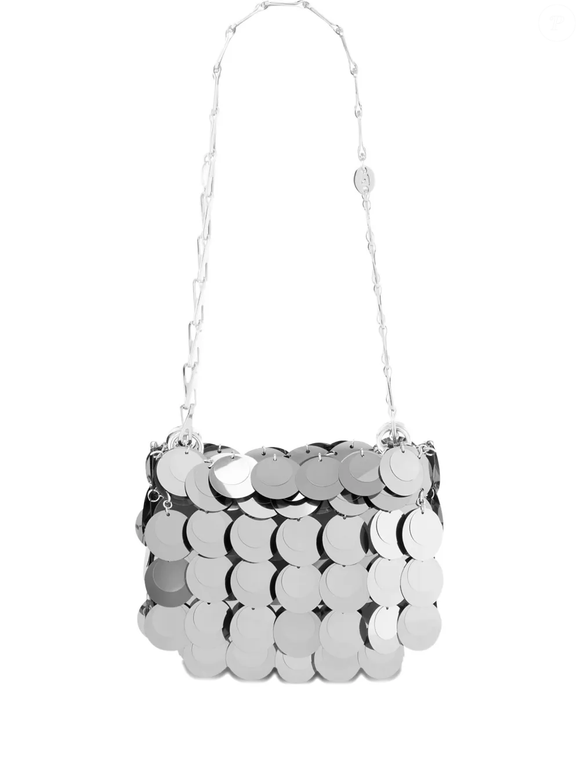 A bolsa de ombro prateada da Rabanne, disponível na Farfetch por R$ 7.314, apresenta placas metálicas com acabamento polido e alça de corrente, detalhes que acrescentam brilho às produções com tênis brancos