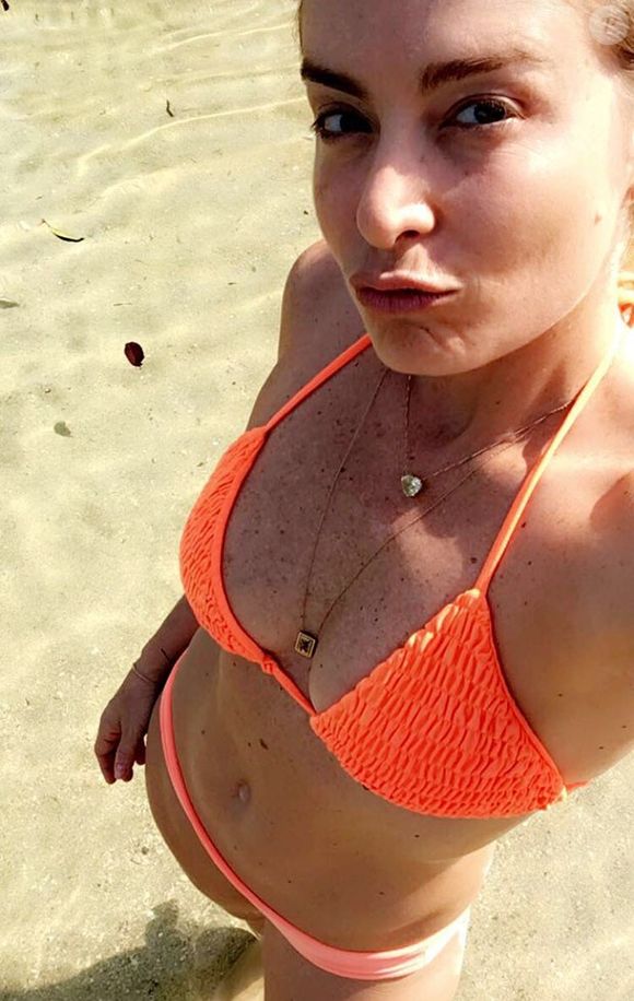Um exemplo disso é este biquíni laranja neon em que, nesta foto, Angélica valorizou sua barriga