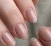 O glitter prateado sobre base nude rosada moderniza a manicura neutra com brilho frio e contemporâneo, ideal para peles de tom frio