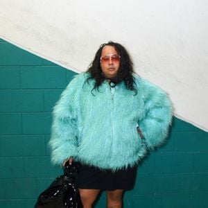 Jup do Bairro roubou a cena ao investir em um imponente casaco peludo de pelos sintéticos em tom azul-turquesa vibrante. A artista equilibrou o volume da peça principal com uma saia preta curta, meias cano alto cor-de-rosa e tênis esportivos brancos