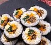 O kimbapm, conhecido como 'sushi coreano', é um enrolado feito com arroz e recheado com diversos ingredientes, incluindo carne, ovo e vegetais, envolto por uma folha de alga marinha