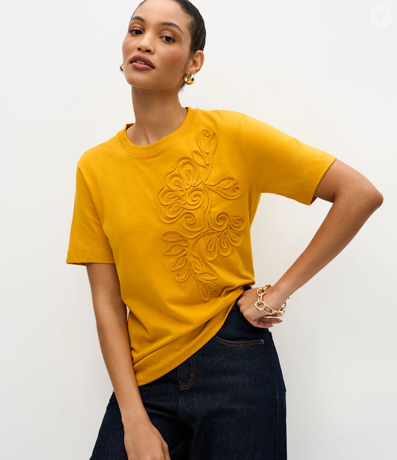 A blusa amarela da Renner, com bordado floral, traz um toque vibrante ao look e cria um contraste charmoso com o tom café com leite amêndoa do Converse Floral Crochet