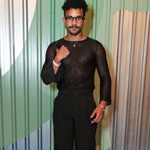 O ator Lucas Leto explorou a sensualidade masculina contemporânea com um look monocromático preto focado em texturas. Ele utilizou uma blusa de manga longa em tecido canelado com leve transparência e brilho discreto, evidenciando o físico de forma elegante. A peça foi combinada a uma calça de alfaiataria de corte reto e cintura alta, mantida por um cinto fino