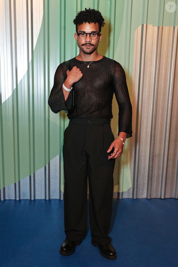 O ator Lucas Leto explorou a sensualidade masculina contemporânea com um look monocromático preto focado em texturas. Ele utilizou uma blusa de manga longa em tecido canelado com leve transparência e brilho discreto, evidenciando o físico de forma elegante. A peça foi combinada a uma calça de alfaiataria de corte reto e cintura alta, mantida por um cinto fino