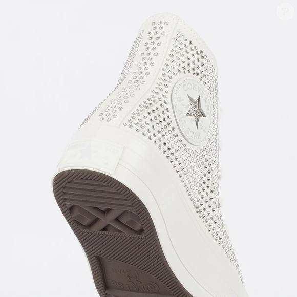 A descrição do produto destaca que a Swarovski, marca austríaca reconhecida mundialmente por sua excelência artesanal, assina o acabamento do tênis, acrescentando glamour e requinte ao tradicional modelo da Converse