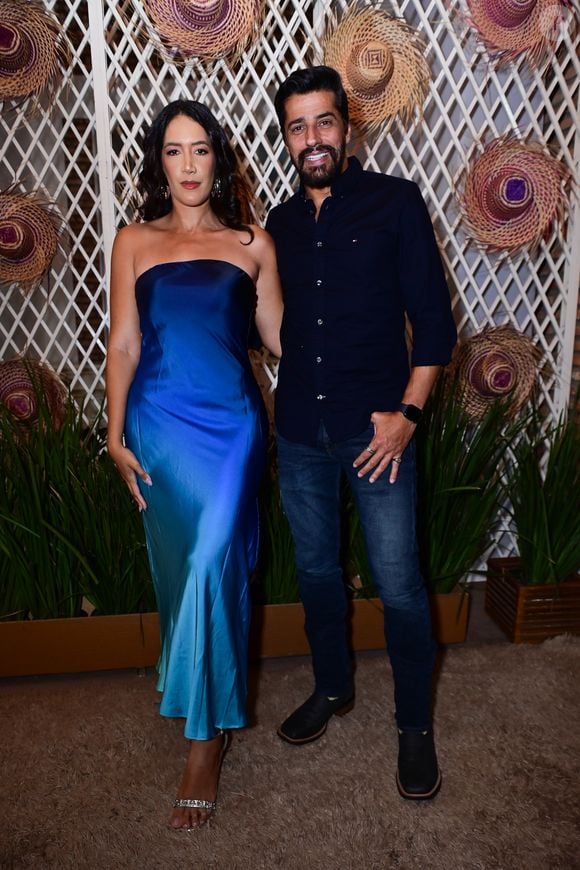 Alberto Cowboy e Priscilla Monroy: o ex-BBB combinou a informalidade da calça jeans escura com uma camisa social azul-marinho de botões e botas pretas de bico quadrado. Sua acompanhante usou um vestido midi tomara que caia em cetim fluido com efeito degradê que transiciona do azul-royal para o turquesa, finalizado com sandálias de strass