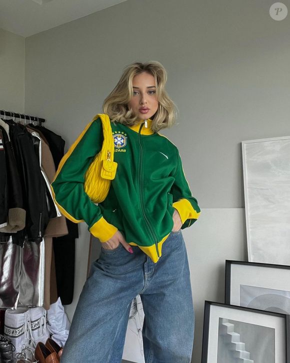 Tendência brasilcore de volta na Copa do Mundo de 2026: Malu Borges apostou em um casaco da Brazil national football team combinado com jeans e bolsa amarela, criando uma produção com irresistível vibe retrô e cheia de personalidade para torcer pelo Brasil com estilo