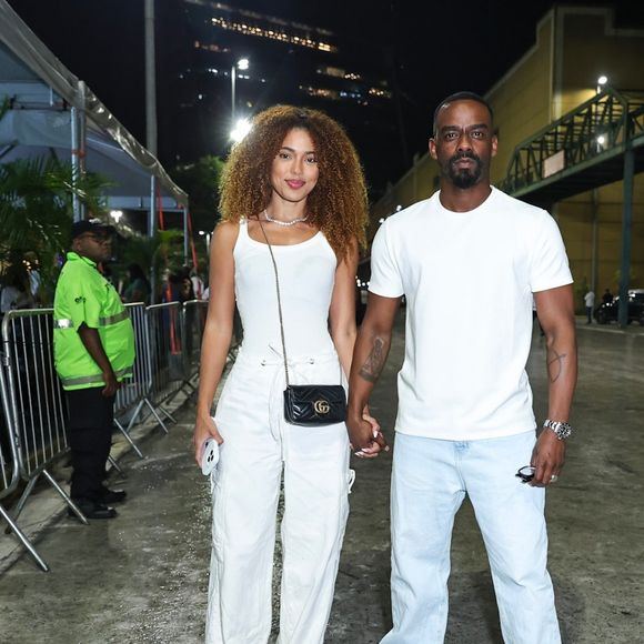 Rafael Logan e Natália Gibson apostaram em um visual coordenado em tons neutros e casuais. Natália vestiu regata branca ajustada com calça cargo ampla branca e bolsa tiracolo preta da Gucci com alça de corrente, enquanto Rafael optou por camiseta básica branca, calça jeans reta em lavagem clara e tênis brancos estilo casual