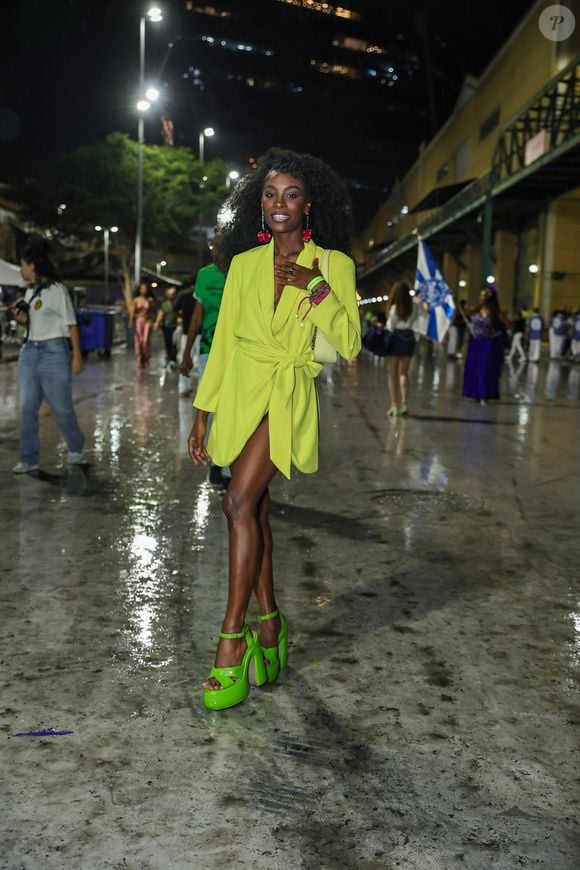 Jennifer Dias apostou em um blazer alongado em tom verde-lima vibrante, usado fechado com amarrações na cintura na proposta de vestido curto com decote acentuado. Para arrematar o visual monocromático nos pés, usou sandálias de plataforma com salto bloco no mesmo tom do blazer, além de bolsa de ombro clara, brincos e pulseiras em tons contrastantes de rosa