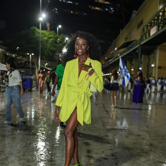 Jennifer Dias apostou em um blazer alongado em tom verde-lima vibrante, usado fechado com amarrações na cintura na proposta de vestido curto com decote acentuado. Para arrematar o visual monocromático nos pés, usou sandálias de plataforma com salto bloco no mesmo tom do blazer, além de bolsa de ombro clara, brincos e pulseiras em tons contrastantes de rosa