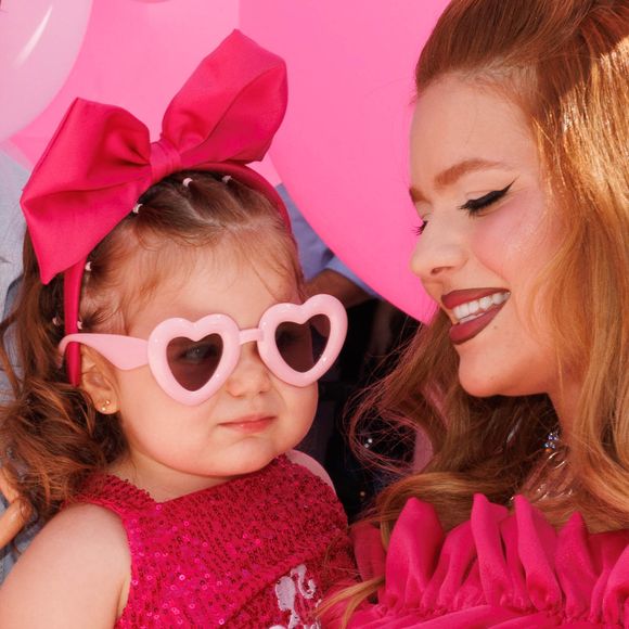 A pequena apareceu com um look digno de tapete rosa: body de paetê rosa com a palavra “Barbie” estampada, saia de tule, laço na cabeça e óculos de sol em formato de coração
