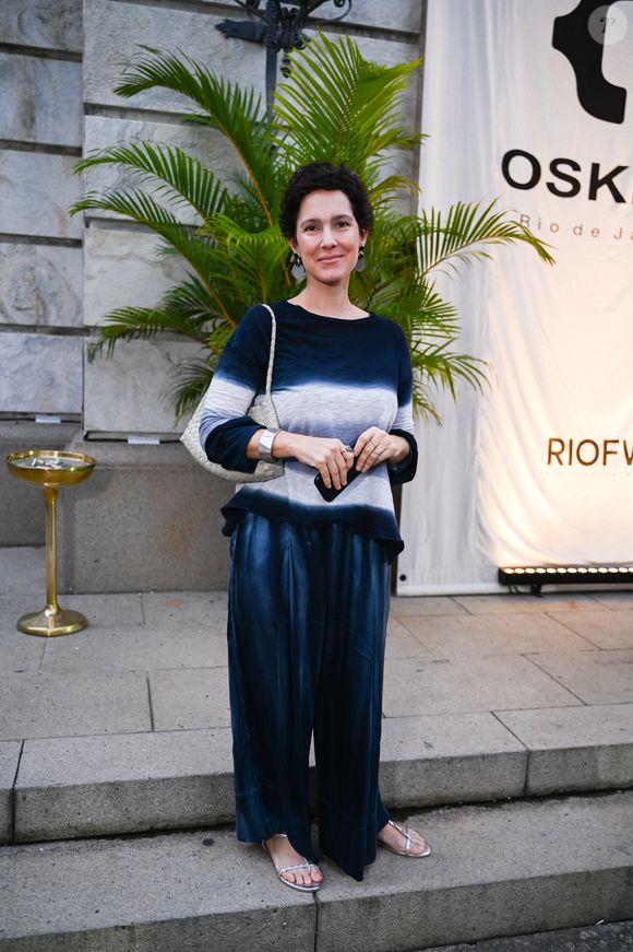 Cecília Malan: exibindo uma elegância despojada e artística, a jornalista optou por um conjunto de duas peças com forte inspiração no movimento tie-dye sofisticado. A blusa de manga longa apresenta degradês horizontais em tons de azul-marinho, branco e cinza, harmonizando perfeitamente com a calça pantalona de cetim azul profundo, que confere um brilho acetinado e movimento ao caminhar