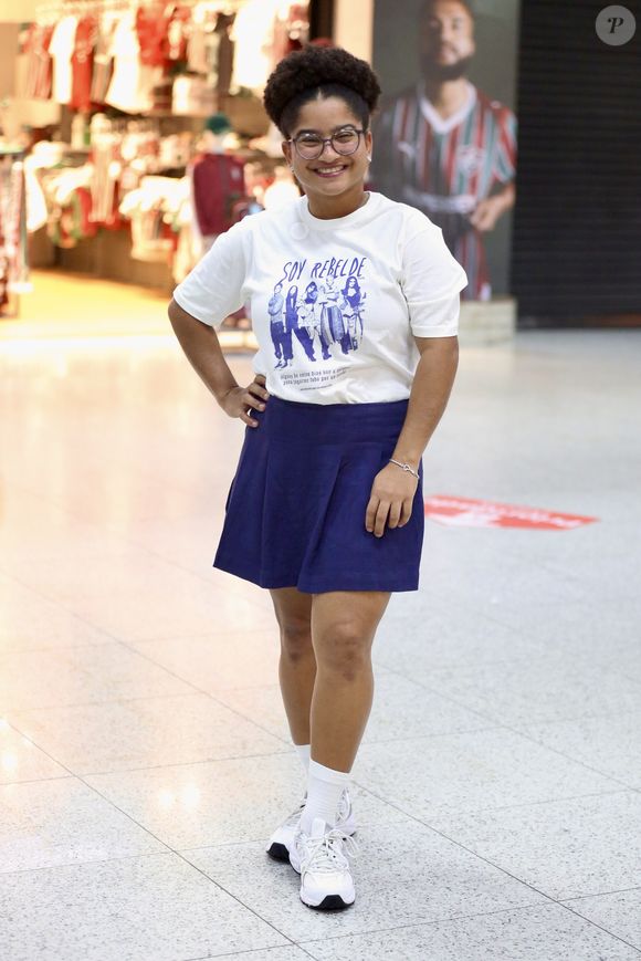 Tia Milena surge sorridente no aeroporto e rouba a cena com combinação fashion de saia plissada e tênis retrô