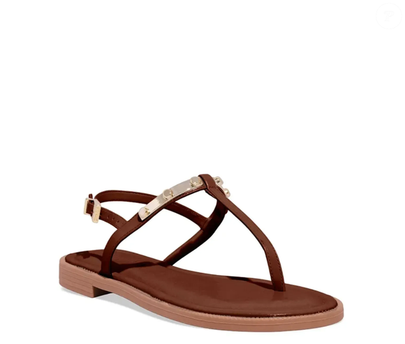 A sandália Rasteira Napa Madri Marrom da Santa Lolla possui um calçado com aplicação de tachas acima do calçado, além de um pequeno salto, ótima para ser usada em produções mais elegantes.