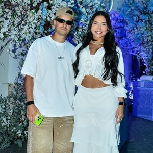 Entre os convidados do chá de bebê, Tainá Costa e Coringa (Victor Augusto) chamaram atenção pelos looks. A cantora optou pelo estilo boho chic, apostando em uma saia fluida em camadas de babados, enquanto o influenciador se destacou com uma bermuda bege decorada com aplicações de strass e brilhos