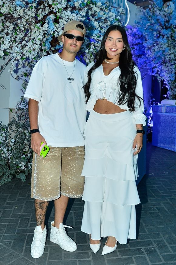 Entre os convidados do chá de bebê, Tainá Costa e Coringa (Victor Augusto) chamaram atenção pelos looks. A cantora optou pelo estilo boho chic, apostando em uma saia fluida em camadas de babados, enquanto o influenciador se destacou com uma bermuda bege decorada com aplicações de strass e brilhos