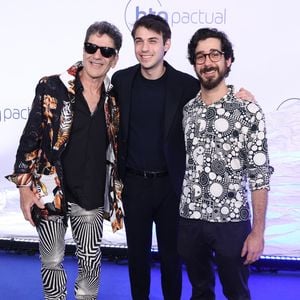 Jorge Israel, Dani Flomin e Leo Israel: Jorge (à esquerda) combina blazer estampado com tigres, calça de padronagem geométrica psicodélica em preto e branco e óculos escuros. Dani (ao centro) usa terno azul-escuro minimalista com camiseta e tênis branco. Leo (à direita) veste camisa de botões com estampa de círculos preto e branco e calça jeans escura