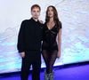 Juliano Floss, do BBB 26, e a cantora Marina Sena, sua namorada: ele veste um conjunto minimalista preto com jaqueta fechada de gola colarinho e calça de corte reto folgado. Ela optou por um vestido longo preto transparente em tecido texturizado de listras horizontais, com decote em V e detalhe volumoso de franjas felpudas cinzas nos tornozelos