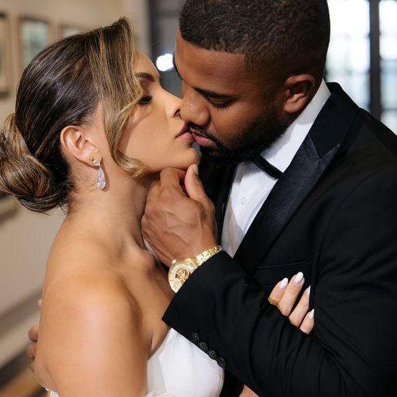 Enquanto Emilly Araújo escolheu um vestido marcado por flores e volume, Davi Brito seguiu uma proposta clássica com um smoking preto sob medida e lapela cintilante